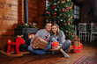 © Andrii - family on the floor against the background of a Christmas tree with gifts