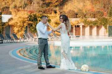 Wedding anniversary young nice people. Young couple in love. A love story by the pool. Lovely couple having fun in autumn time. Guy kisses girl's hand