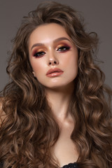 Young sexy brunette model with professional makeup, perfect skin, volume hairstyle. Colorful smoky eyes.