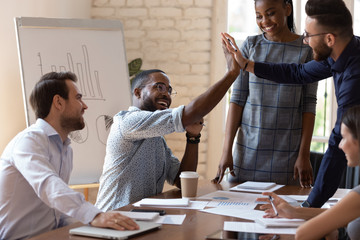 Canvas Print - Happy african american male manager giving high five to arabian colleague.