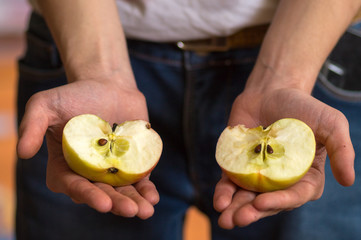 Two halves of an Apple in the hands of a young man close-up. Horizontal arrangement.