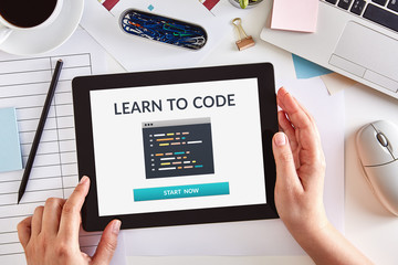 Wall Mural - hands using a digital tablet computer with learn to code concept on screen over business desk. top v