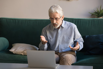 Elderly man makes video call talking looking at computer screen