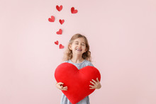 Cute Little Girl With Pillow In Shape Of Heart On Color Background. Valentines Day Celebration