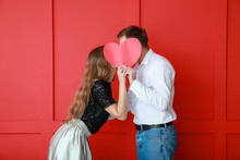 Happy Young Couple With Red Heart On Color Background. Valentine's Day Celebration
