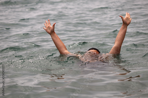 Gestures of a drowning man calling for help at sea. Horizontal, cropped picture, close-up. Water safety concept.