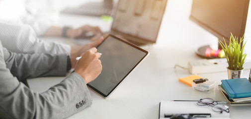 Cropped shot of professional UI web developer team working on their project with tablet in modern workplace