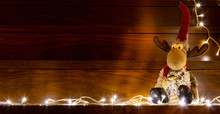 Christmas Concept, Santa Claus And Teddy Reindeer On Wood Background With Christmas Lights Around.