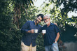 © chokniti - An adult hipster son and his senior father in garden, hugging