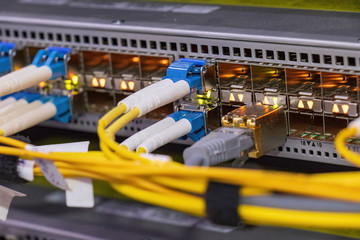 Network fiber cables connected to switch - closeup of data center hardware. Shot of network cables and servers in a technology data center. 