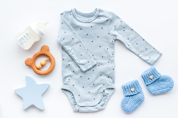 newborn baby boy set - blue clothes as bodysuit, booties, toys - on white table top-down