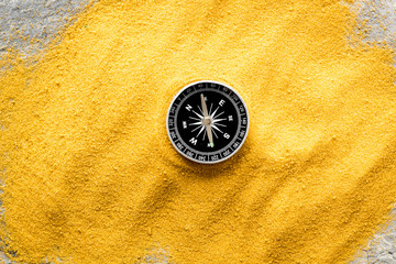 Wall Mural - Travel concept. Compass on yellow sand background top view copy space