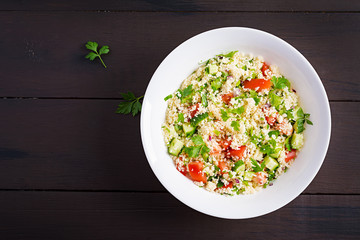 Traditional Lebanese Salad Tabbouleh. Couscous with parsley, tomato, cucumber, lemon and olive oil. Middle Eastern cuisine. Top view, copy space