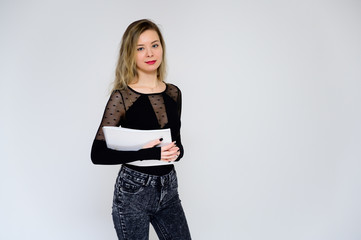 Concept of a woman talking to the camera. A photo of a pretty smiling girl with curly hair in a black T-shirt on a white background is standing right in front of the camera with a folder in her hands.