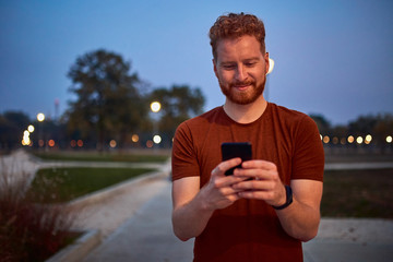 Man using cellphone in urban park at night.