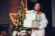 © prostooleh - Beautiful girl in a decorated room. Woman near Christmas tree. Black lady in a white blouse