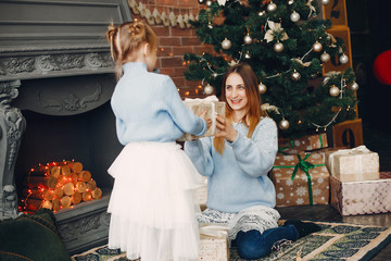 Beautiful mother in a blue sweater. Family with cristmas gifts. Little girl near christmas tree