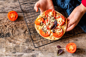 child cook homemade pizza. Home made pizza topped with tomatoes, spices and fresh basil. Symbolic image. Concept for a tasty and hearty meal. Wooden background.