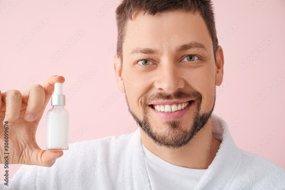 Handsome man with cosmetic product on color background
