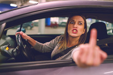 Young Woman Driver Showing Middle Finger Trough The Window Of The Car Mad Angry Furious Pissed On The Parking In The City At Night Driving