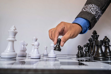 hand of businessman moving chess in competition, shows leadership, followers and business success strategies