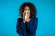 Young girl with afro hair sneezes into tissue. Isolated woman is sick, has a cold or has allergic reaction. Health, medicine, illness, treatment concept