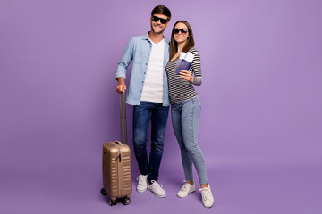 Wall Mural - Full length photo of two people couple guy lady walking airport registration tickets passports baggage vacation time wear stylish casual clothes isolated pastel purple color background