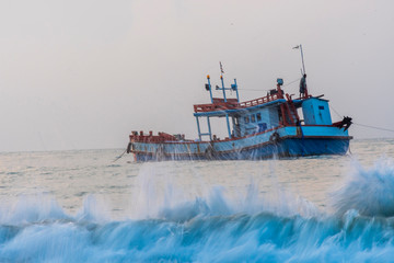 The image of a fishing boat floating in the sea in the blue sea.