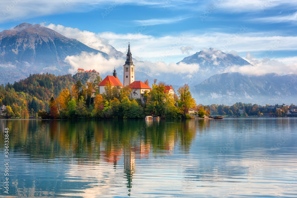 Famous alpine Bled lake (Blejsko jezero) in Slovenia, amazing autumn landscape. Scenic view of the lake, island with church, Bled castle, mountains and blue sky with clouds, outdoor travel background - obrazy, fototapety, plakaty 