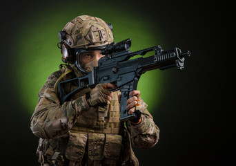 a male soldier in military clothes with a weapon on a dark background in a gas mask