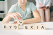 © LIGHTFIELD STUDIOS - cropped view of kid with dyslexia sitting at table and playing with wooden cubes