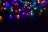 Fototapeta Pokój dzieciecy - Christmas background with lights and free text space. Christmas lights border. Glowing colorful Christmas lights on black background. New Year. Christmas. Decor. Garland.