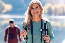 Pretty Young Female Hiker Smiling While Looking At Camera In Front Of Lake.