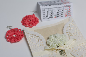 Wall Mural - Handmade crocheted earrings. Greeting card. Nearby is a fragment of the calendar with the month of December. On white background.