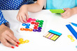 © volurol - Mother with kid plays logical games, close up, top view. Child training mind with plastic colored puzzles on white table