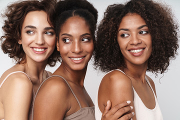 Wall Mural - portrait of three charming multiethnic women smiling and looking aside
