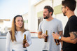© Mangostar - Group of friends chatting and drinking beer on outdoor terrace. Young men and woman in casual meeting outside. Leisure time and weekend concept