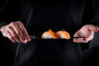 Sushi served on japanese knife in chef hands on dark background. Decorated salmon sashimi nigiri. Traditional japanese food. Copy space for text