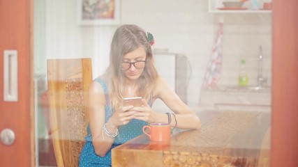 Woman using cellphone inside house and drinking coffee / tea.