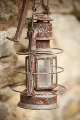 old rusty kerosene lamp hanging on stone background