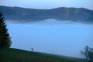 Man standing and looking at beautiful misty landscape and mountains