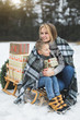 © sofiko14 - Mother with little son in winter park sledging. Mom and child sitting together on wooden decorated sledge with Christmas presents. Winter walk outdoors