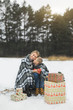 © sofiko14 - Mother and baby sitting on wooden sledge in winter forest and drinking hot tea. Christmas gifts presents on the snow. Winter snowy forest on the background. Christmas vacation.