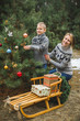© sofiko14 - Mother and her little son decorating Christmas tree outdoors in winter forest. New Year, Christmas and family concept