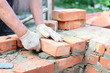 Bricklaying house wall,  masonry. Bricklayer hands in masonry gloves bricklaying house wall.