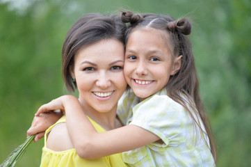 Wall Mural - Portrait of young mother and daughter hugging in autumn park