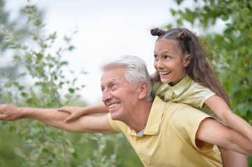 Poster - Portrait of happy grandfather and granddaughter having fun in park