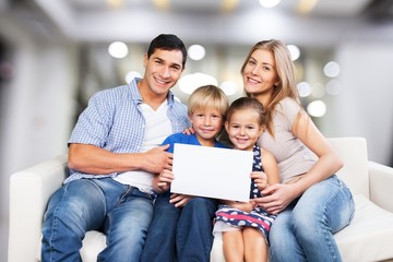 Canvas Print - Beautiful smiling family sitting at sofa on bokeh background