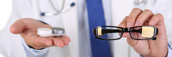 Canvas Print - Male doctor hands giving pair of black glasses and contact lens