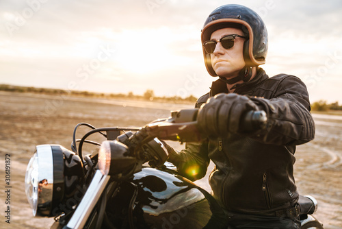 Fotografía Young man biker on bike outdoors at the desert field.